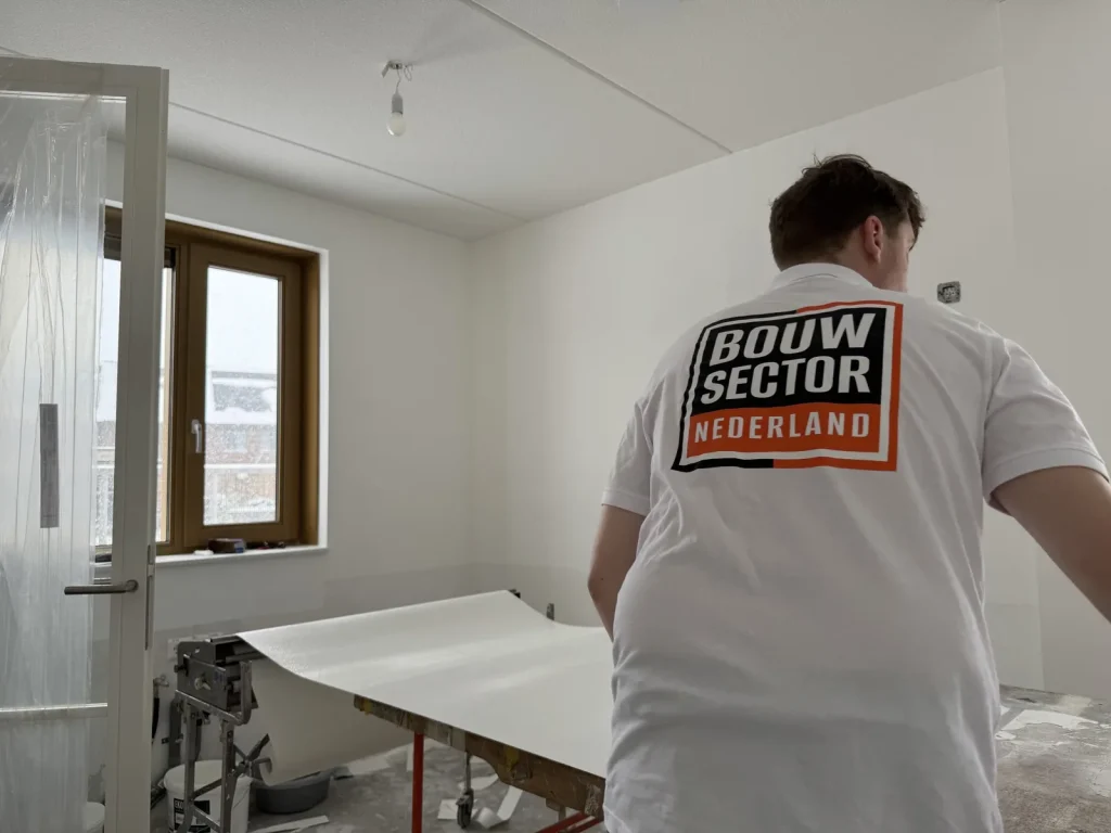 Behanger van Bouwsector Nederland trekt een baan renovlies over de plaktafel