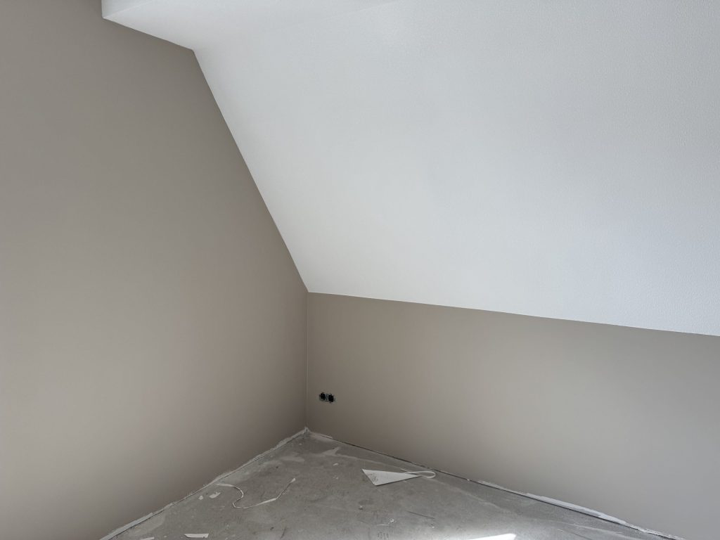 Zolderkamer met schuine wand, afgewerkt in wit en een zandtint